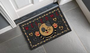 Tappeto con stampa di un gattino stilizzato con scritta "Welcome" con base grigia e stampa beige, rossa e nera.